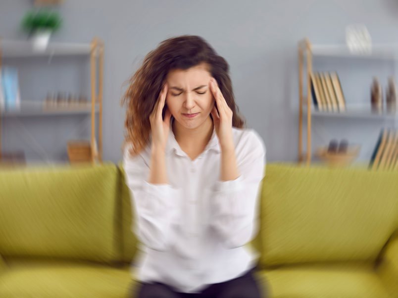 Frau auf dem Sofa hält sich den Kopf